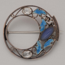Dorrie Nossiter (1893-1977) "Circle" Brooch, sterling set with an oval blue chalcedony cabochon, white quartz jewels and blue enamel leaves, marked, c. 1920