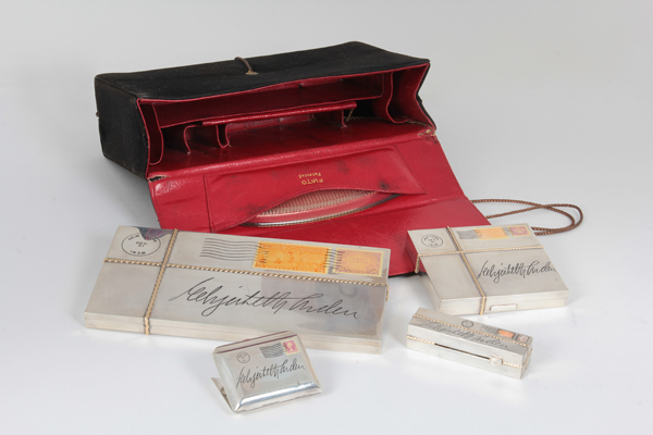 Paul Flato, signed, Important “Elizabeth Arden” Trompe L’oeil black suede and red leather “Wrapped Package” Necessaire containing silver, gold and enamel envelopes, postmarked New York, Dec. 31st, 1938