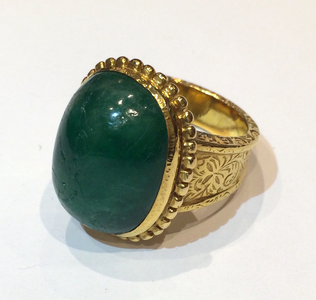 Bhutan natural large cabochon emerald ring (approx. 37 carats TW, G.I.A Certificate, indications of clarity enhancement) in 20-22K gold with decorative incised details and a gold beaded bezel, marked, c.1900