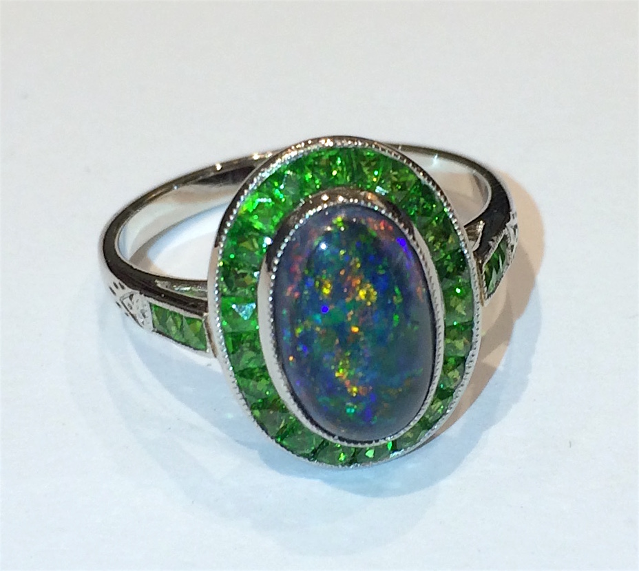 Art Deco Black opal cabochon ring (approx. 2 carats TW) set with 28 French cut demantoid garnets all set in a platinum mounting, marked, c. 1920