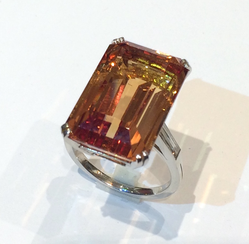 Imperial topaz (26 carats) solitaire ring set in platinum with two elongated baguette diamonds, signed: L and M French maker’s mark in a diamond poincon, French Dog’s head assay mark for platinum, c.1950