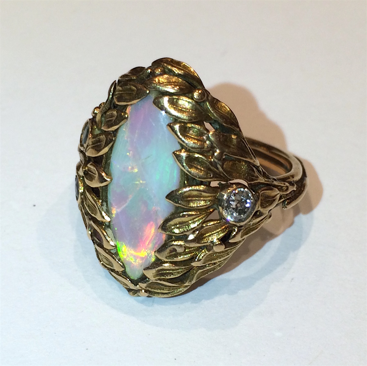 American Arts & Craft “Stylized Leaf” ring, 18K gold set with two demantoid garnets, a diamond and a large marquee shaped cabochon fire opal, c. 1910