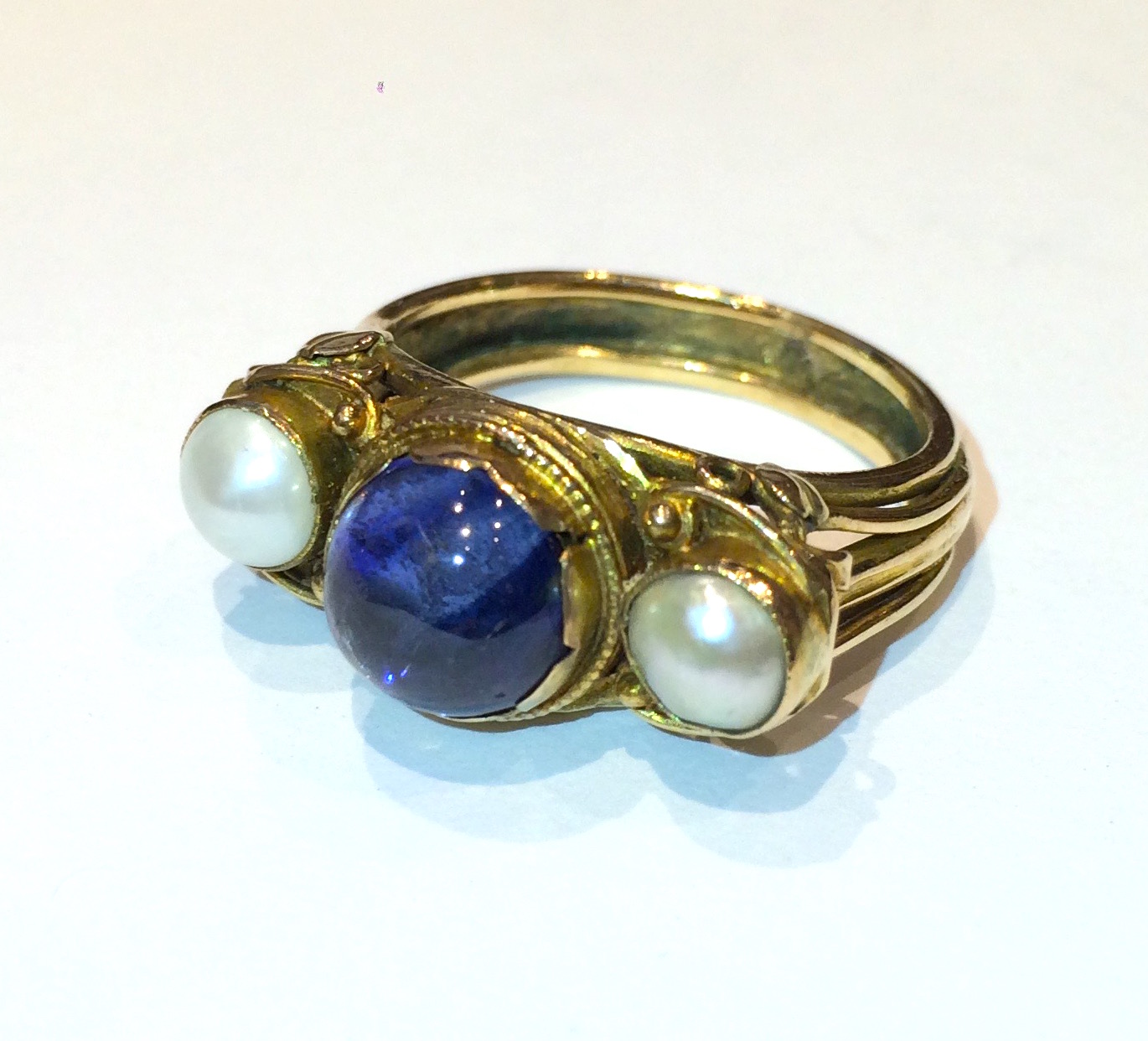 George Hunt (1892-1960) “Arts & Crafts” ring, Hand wrought gold set with a cabochon sapphire (approx. 1 1/2 carats) and two pearls, signed, c. 1920