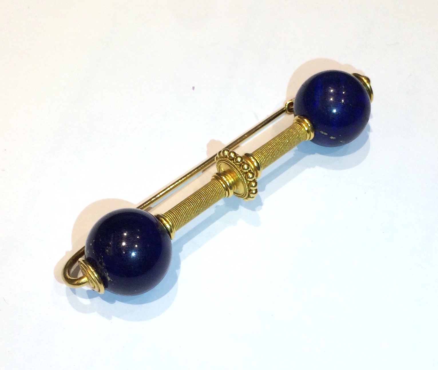 Robert Phillips (attr.) “Etruscan Revival” Fibula brooch in 18K gold with granulation and twisted rope gold details and two large lapis balls, c. 1880