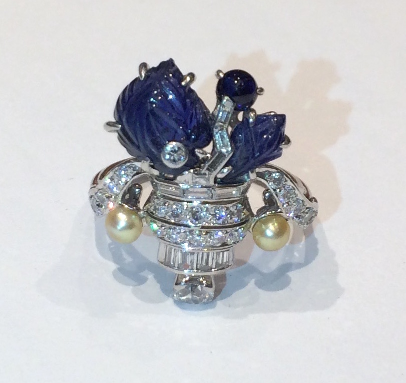 Lacloche Freres, Paris (attr.) Tutti Frutti “Bouquet of Flowers” ring set with two Mughal carved sapphire flower/leaf shaped jewels and further set with a matching cabochon sapphire, 11 baguette diamonds, 22 round cut diamonds and two golden hued pearls all in a very intricately detailed platinum mount, c.1920’s