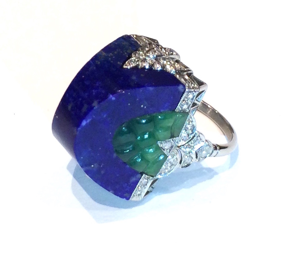 Art Deco “Dome” ring in platinum set with a half-round carved natural lapis-lazuli central stone and further set with two carved green jade jewels inset on either side and 44 round cut diamonds, c.1930’s
