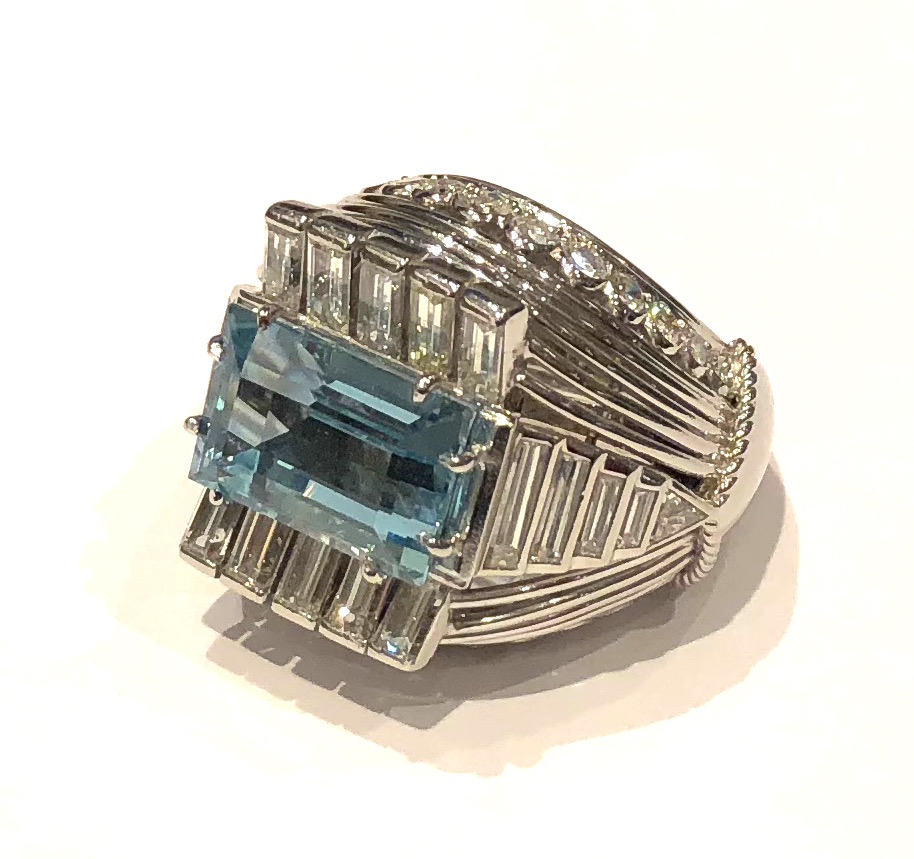 Cartier (attr.) “Bombe” cocktail ring set with a emerald-cut aquamarine (approx. 6 carats TW) 26 round-cut diamonds, 18 baguette diamonds and two triangle-cut diamonds (approx. 6.5 carats TW) all in an elaborate platinum mounting with open platinum wire details, Marked: French “Mask” platinum guarantee mark for remarking old production pieces, c.1950