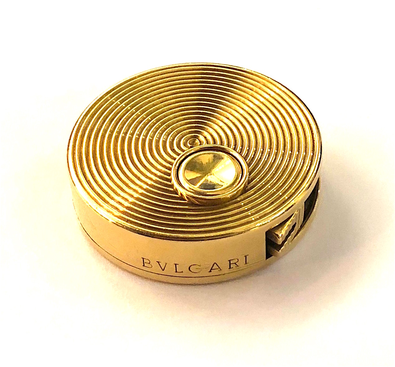 Bulgari, Rome, “Pocket Tape Measure” lighter, 18k gold with a concentric ring detail on both the top and the underside, signed: BVLGARI, BB back to back in a hexagon maker’s mark, 750 (in a rectangle), Swiss made, G. 137, original signed blue leather box with a tan suede interior, c. 1970’s