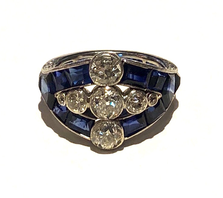 American Art Deco “Triple Diamond” and sapphire ring set with seven round-cut diamonds (approx. 1.20 carats TW) and further set with 24 emerald, square and mixed–cut sapphires (approx. 3.50 carats TW) encircling the ring and all in a finely engraved platinum mounting, c. 1930