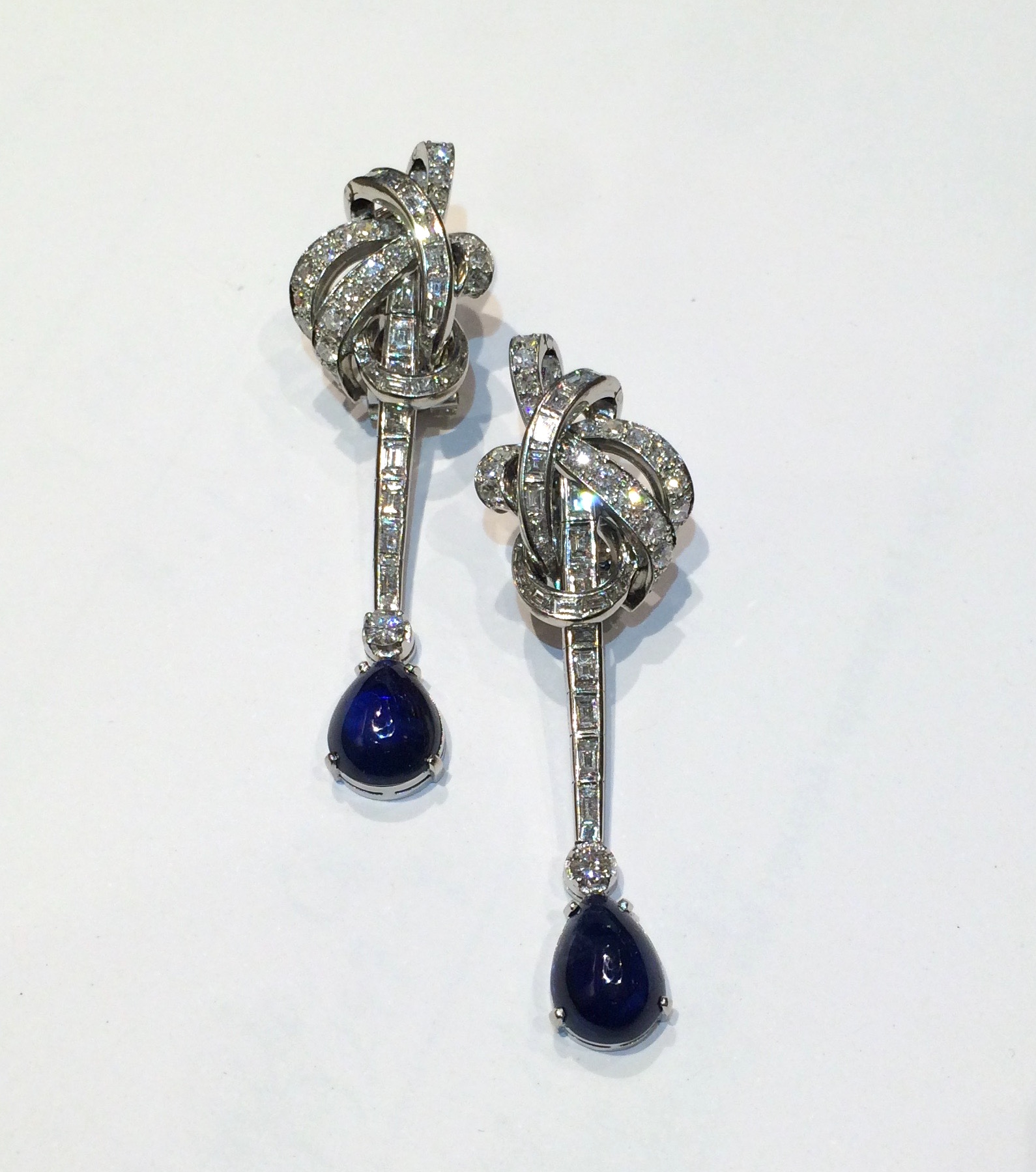 American Pendant “Knot” earrings set with two natural cabochon sapphires (GIA certificate, approximately 6 carats TW) and further set with 50 round diamonds (approx. 6 carats TW) and 48 baguette, square and tapered diamonds (approx. 7 carats TW) all set in platinum mounts, marked, c.1950