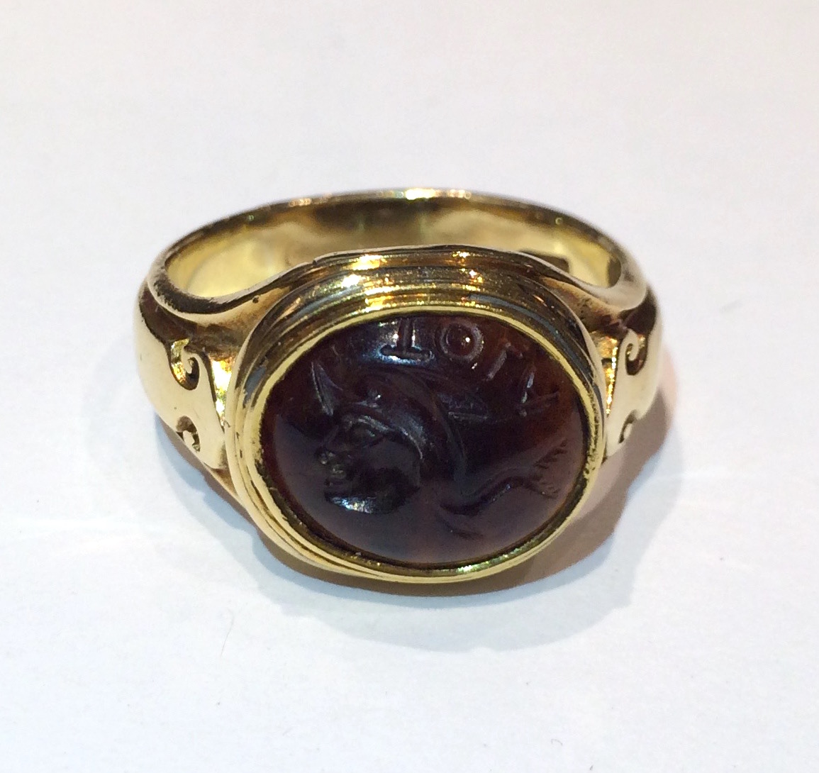 Charles Gordon (reg. London 1828) “Medieval Revival” signet ring, 18K gold with stylized arrow motifs on either side and bezel set with an ancient agate Intaglio carved with the head of a knight and Latin or Greek letters, signed: C.G. for Charles Gordon in a rectangular cartouche, c.1850